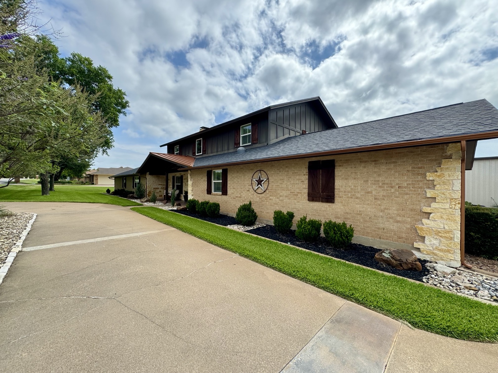 Front exterior showing copper porch roof, Austin Stone, dark board-and-batten upper story