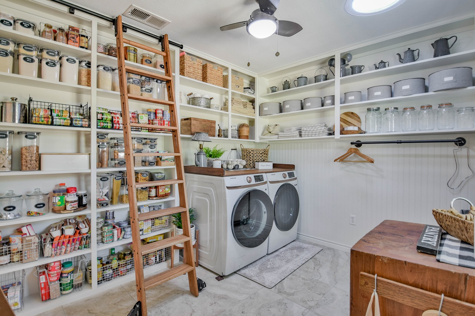 Floor-to-ceiling pantry with rolling library ladder, integrated washer and dryer