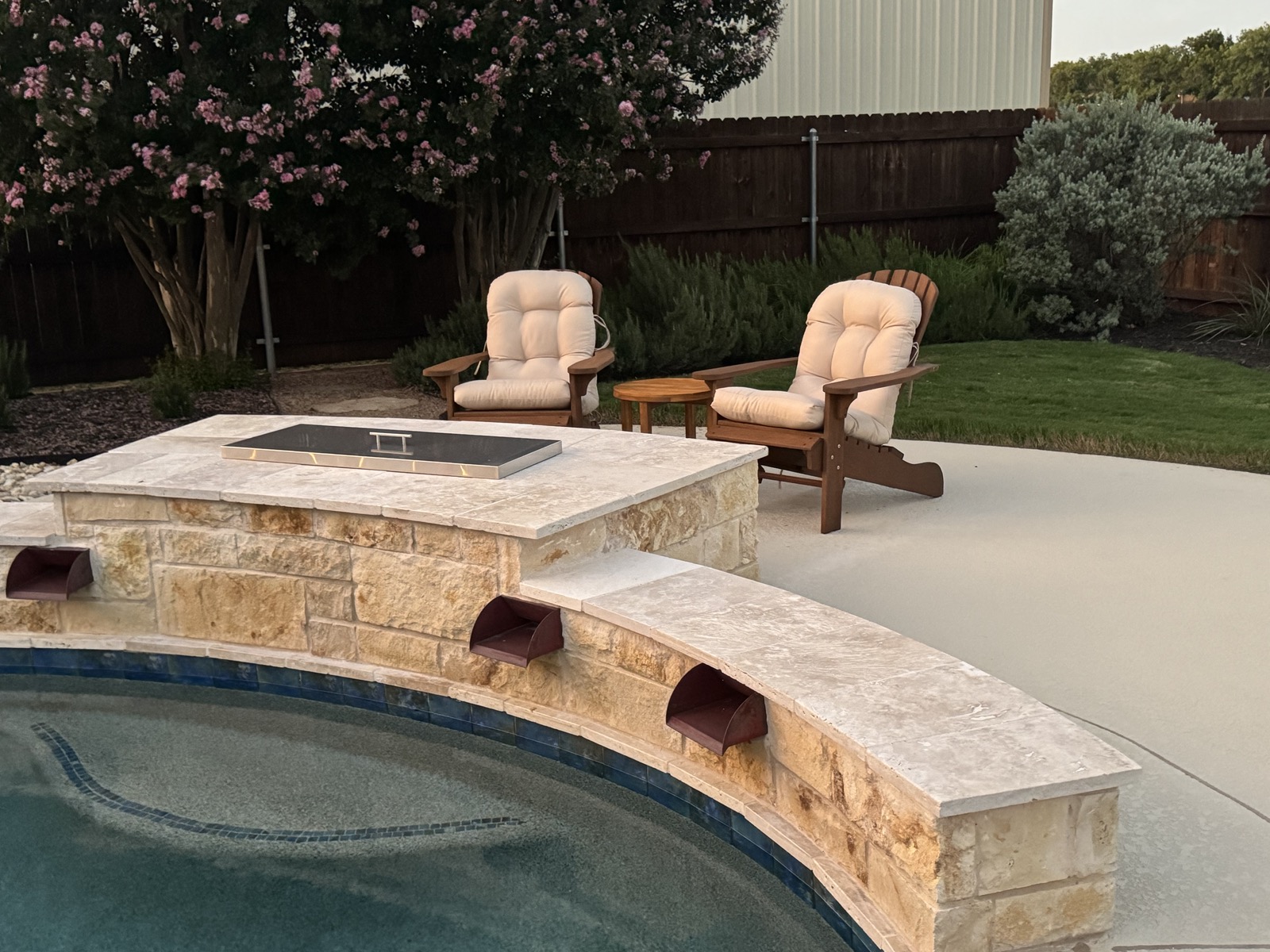 Fire feature water scuppers and pool at dusk with crepe myrtle in bloom